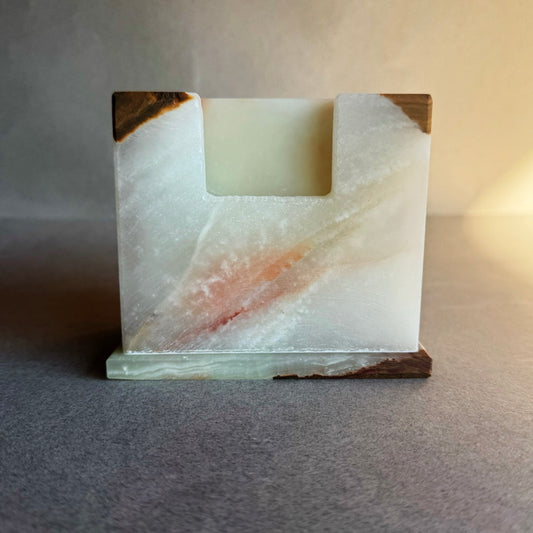 Square stone coaster holder in ivory and cream onyx with subtle rust and brown veining, matte finish.