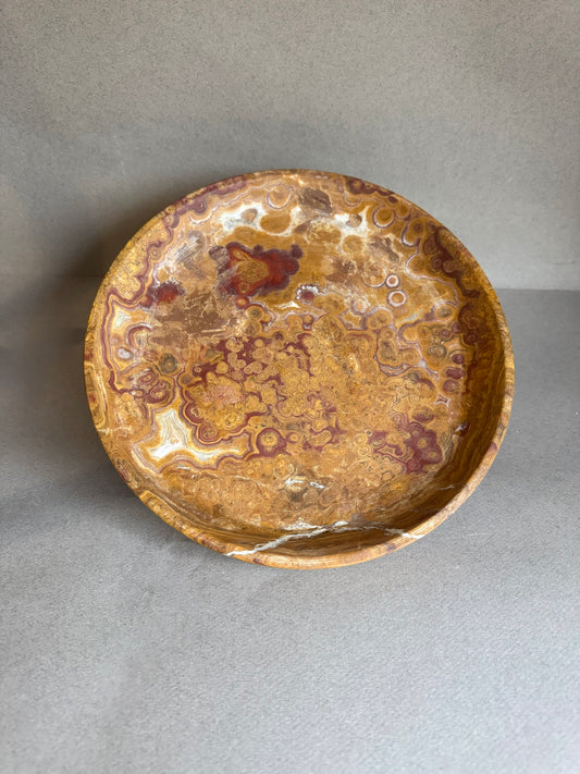 Onyx stone bowl with marbled brown and beige design on a gray background
