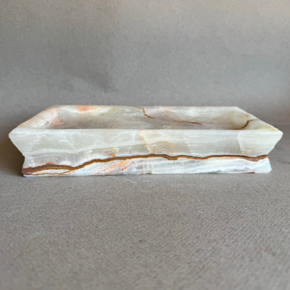 Natural stone vanity tray with warm rust, amber, and beige layers