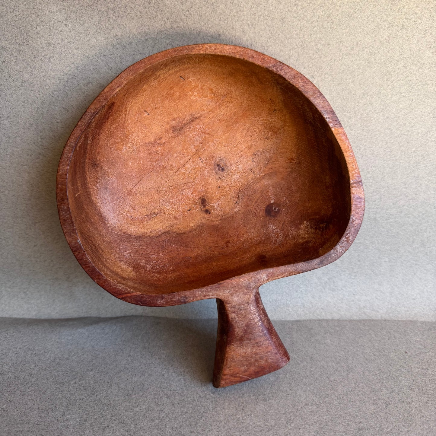 Wooden bowl with a unique mushroom hand carved design on a gray background