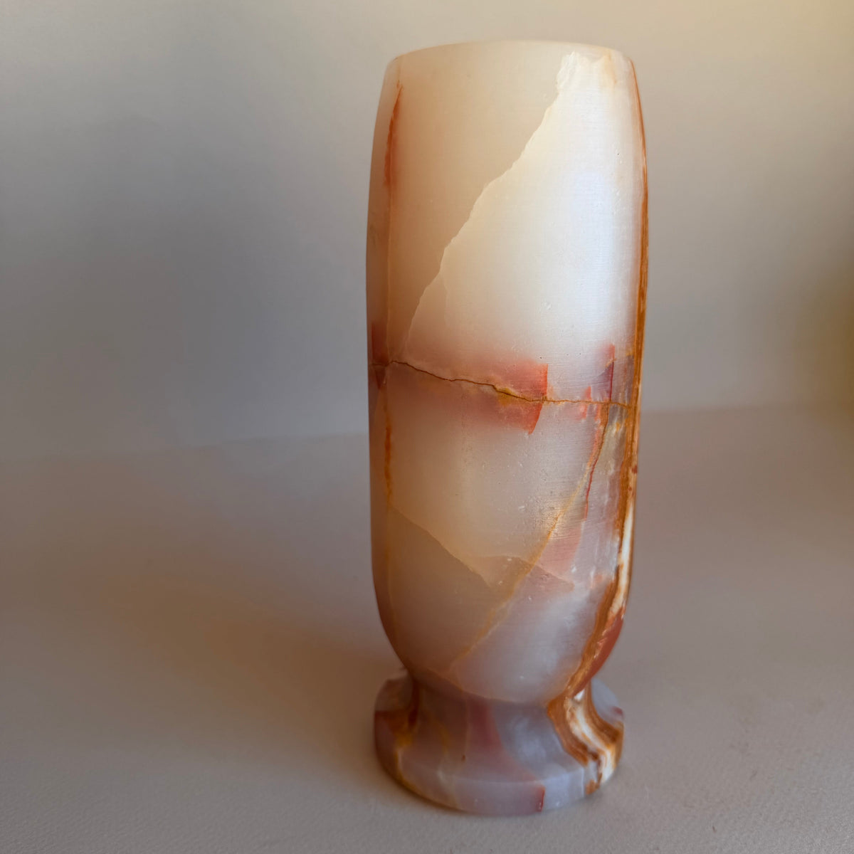 Polished stone onyx vase with a marbled pattern on a plain background