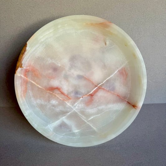 Top-down view of sculptural onyx bowl showing swirling cream, ash, and sage veining