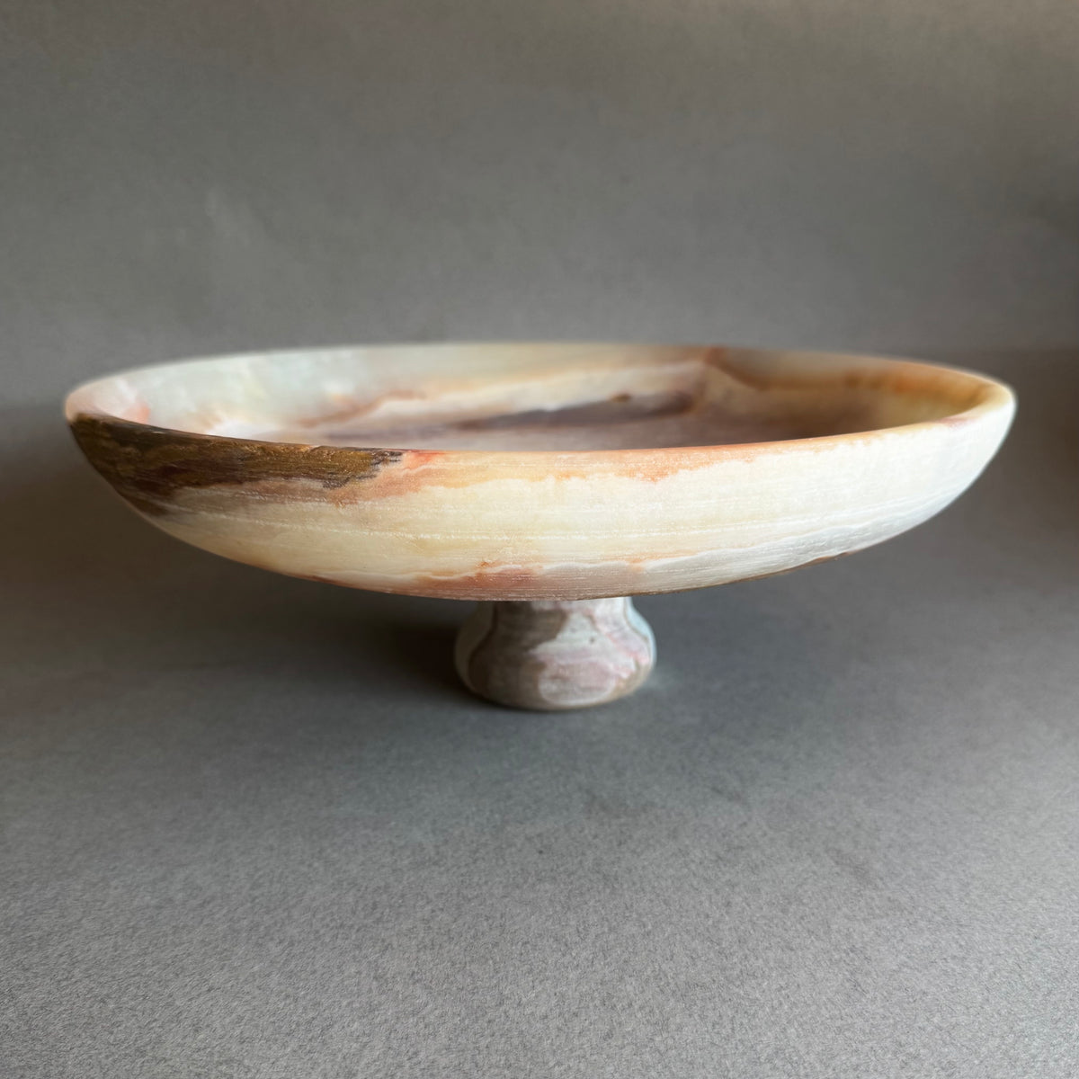 pink onyx Decorative bowl on a stand with a speckled design against a neutral background