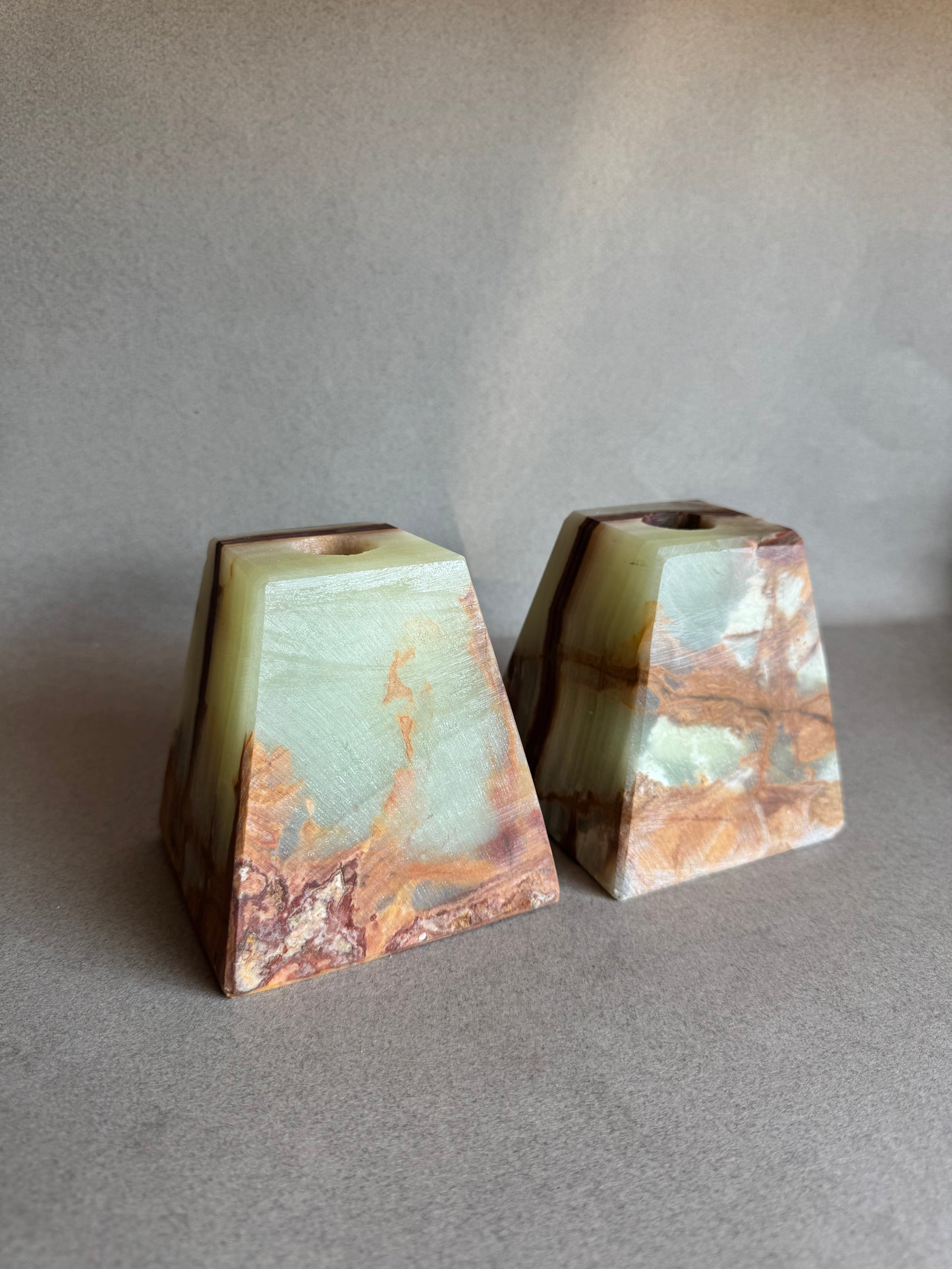 Two square-shaped onyx stones on a reflective surface