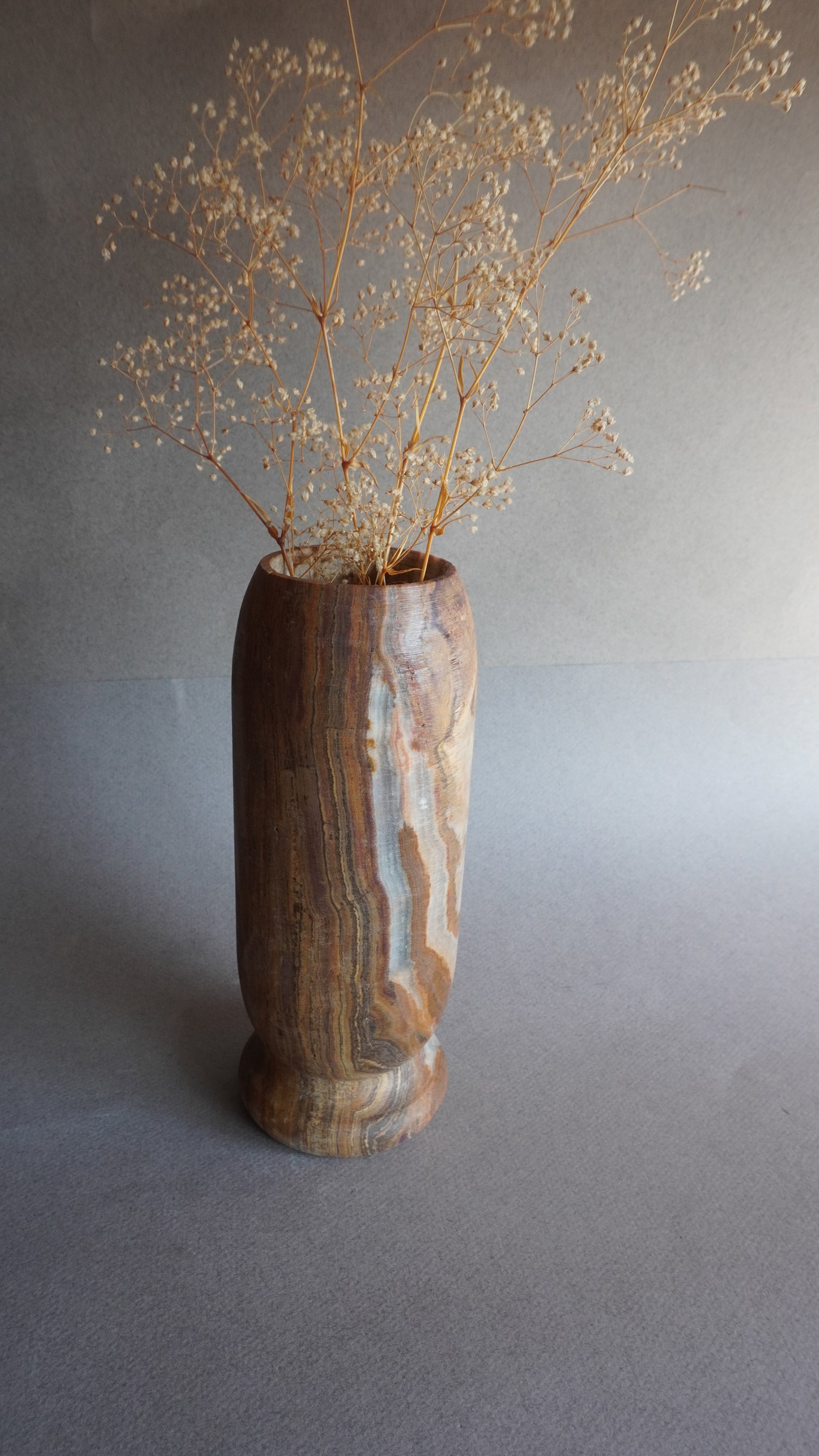 Side view of natural onyx vase with pedestal base, tall stone floral vase for branches, dried flowers, or statement accent