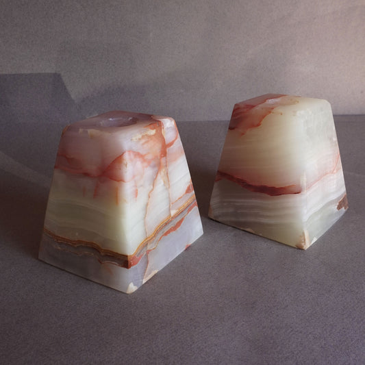 Two marbled stone ONYX candle holders on a gray surface with a neutral background