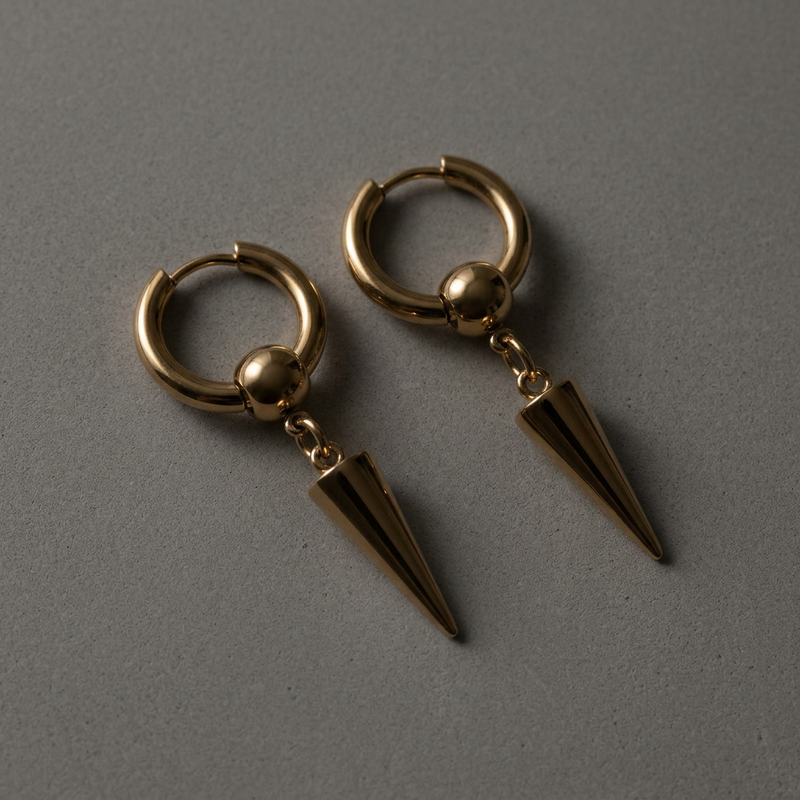 Pair of gold spike drop hoop earrings laid flat, showing hinged hoop and tapered spike drop