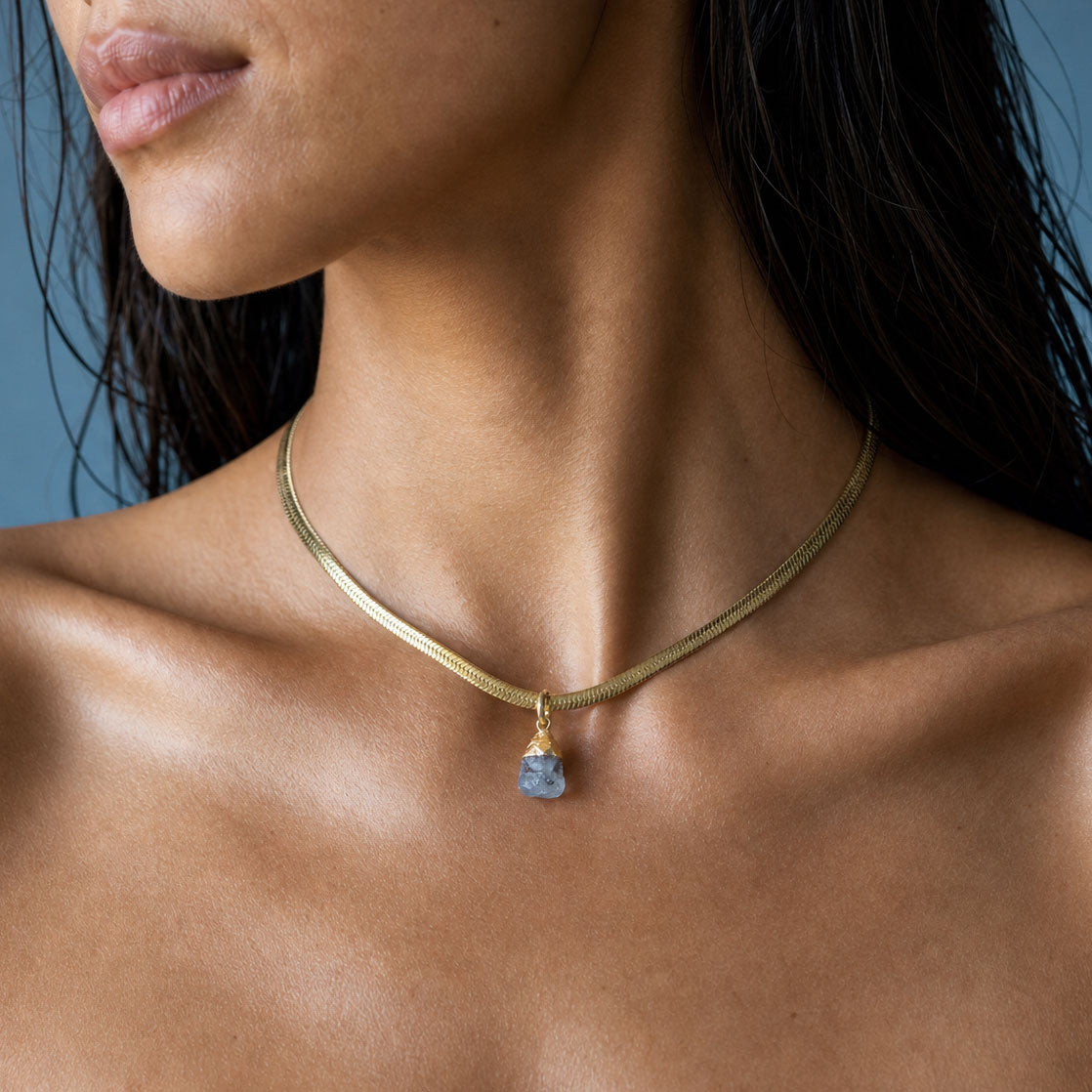 Necklace worn at the base of the throat, a raw herkimer diamond pendant on a flat gold chain.