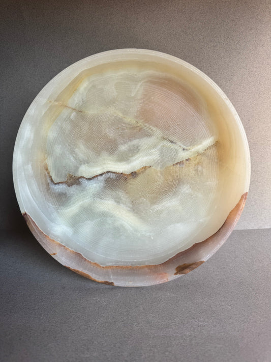 Stone pedestal bowl in ivory and beige with natural brown veining, side view.