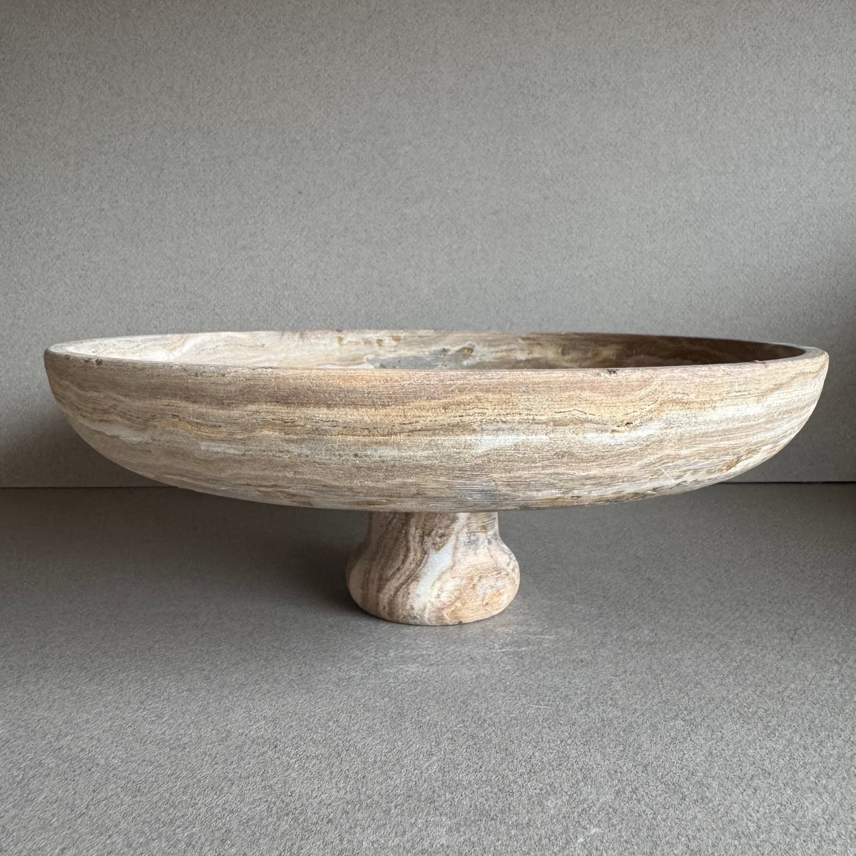 Hand-carved onyx vase in soft walnut, blush, and ivory tones with cylindrical form and pedestal base.