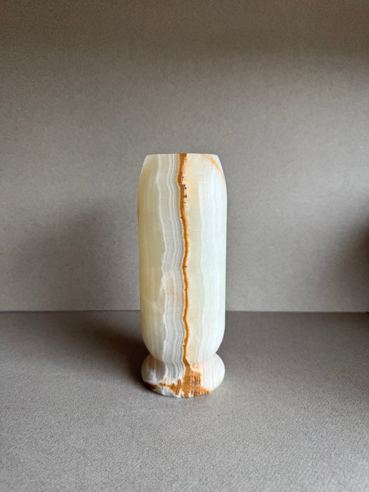 Front view of natural stone vase with warm cream body and rust-colored banding.