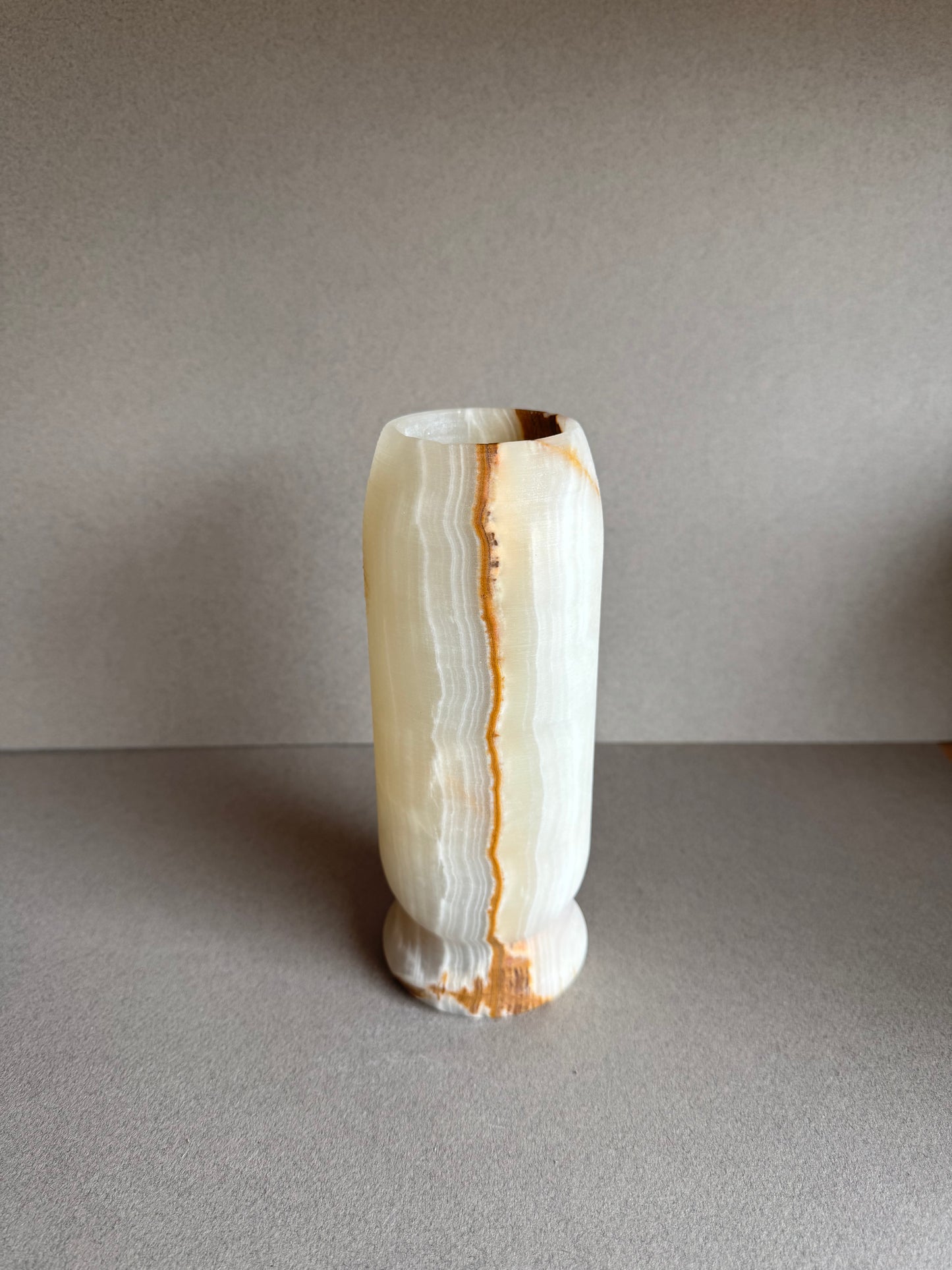 Soft cream-toned side view of vase with light mineral patches and warm base.