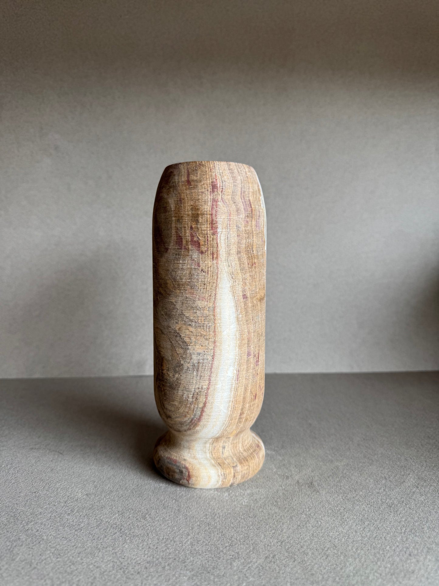 Side view of cylindrical vase highlighting vertical bands of cream, pink, and brown.