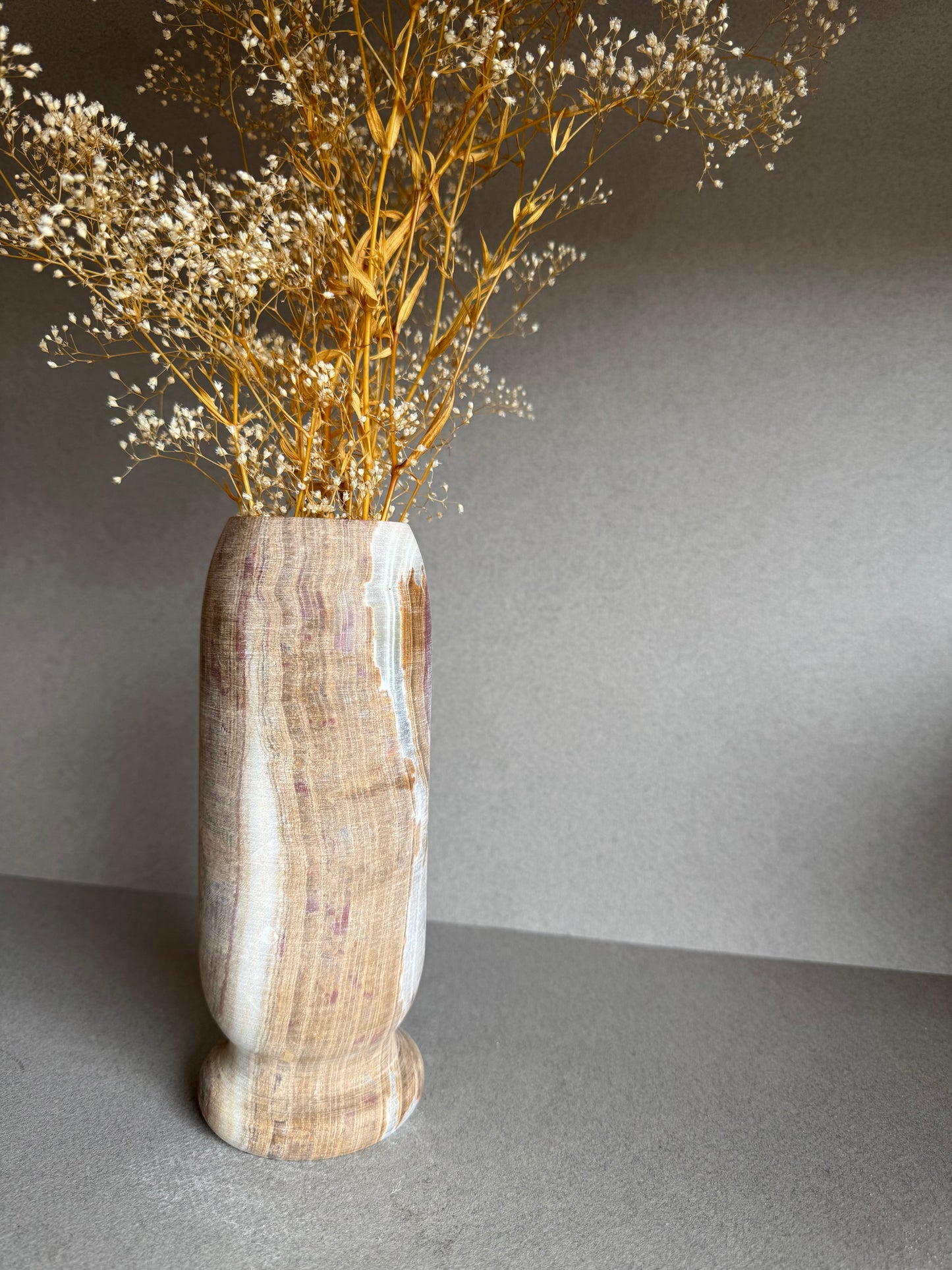 Close-up of floral arrangement in vase, showing texture and natural variation in the stone.