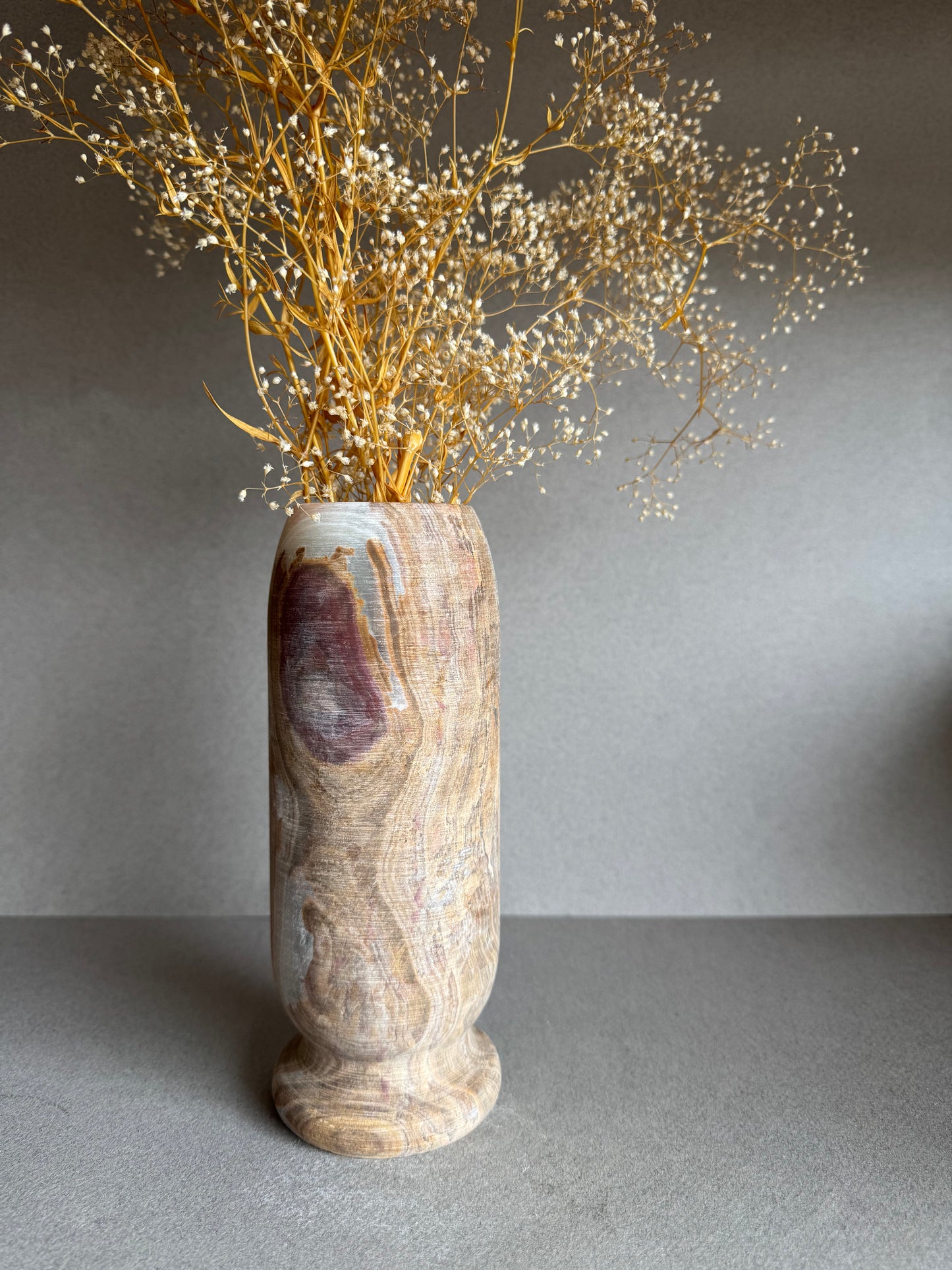 Rosewood-toned vase with dried florals, mineral bloom detail visible near the top.