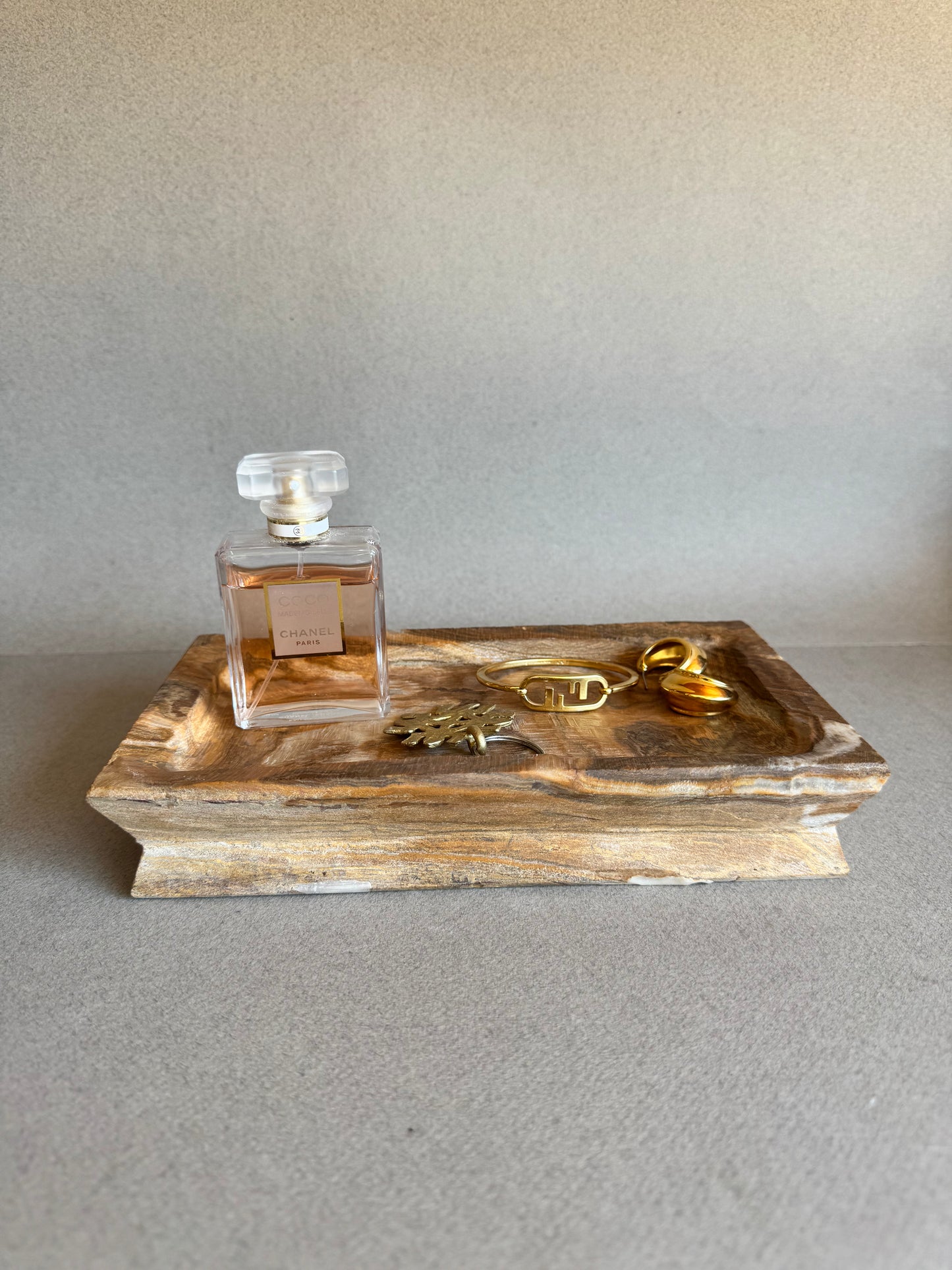 rectangular stone tray with jewelry and perfume