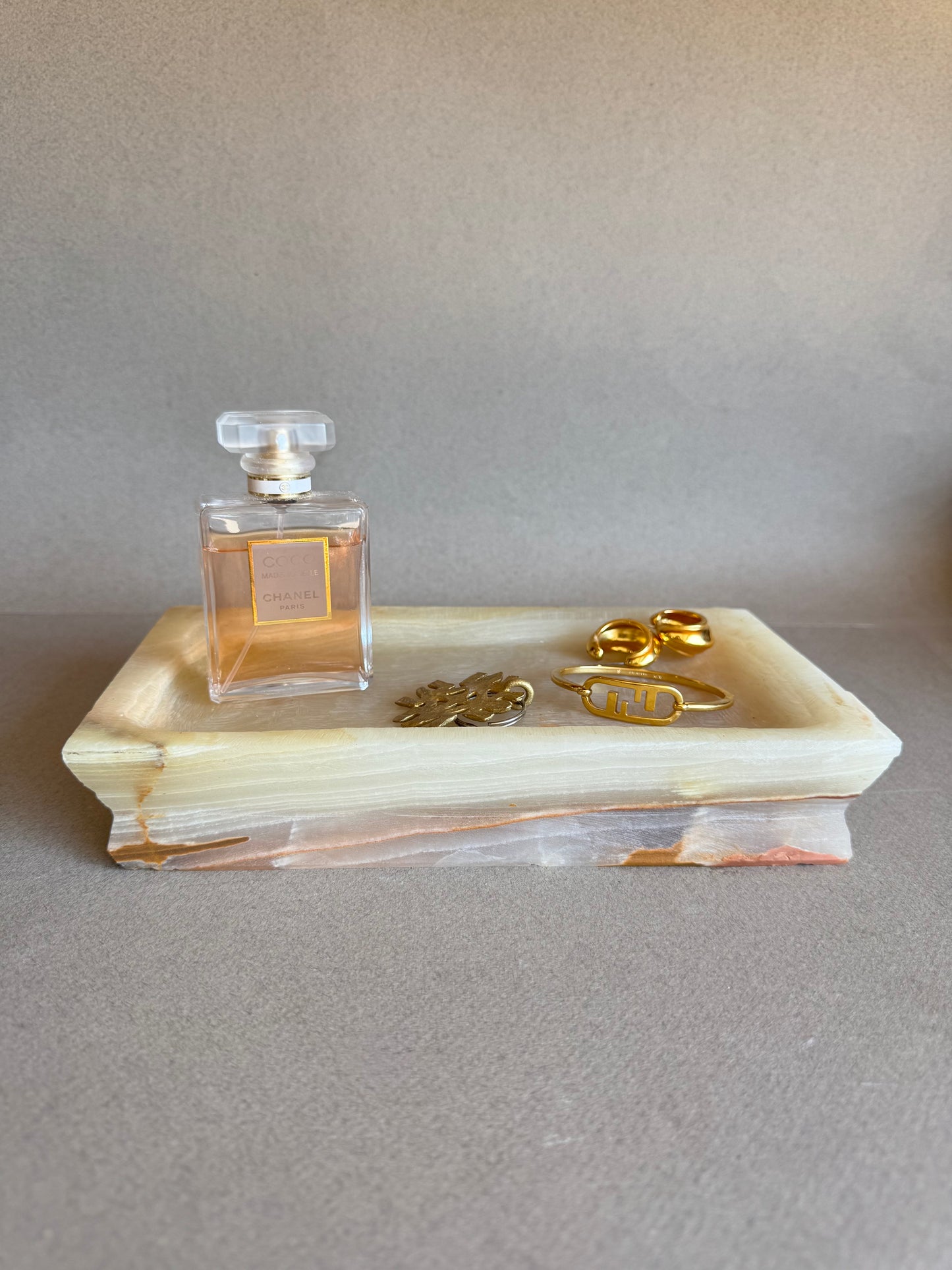 Blush and honey-toned onyx tray used as a sculptural decor piece on tabletop
