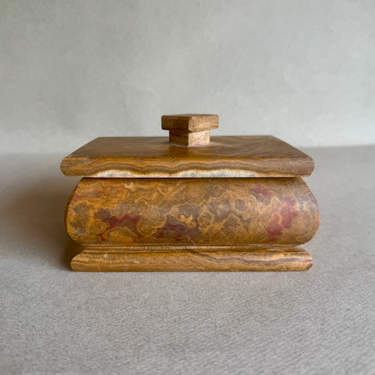 Hand-carved golden amber onyx keepsake box with lid, photographed on neutral background