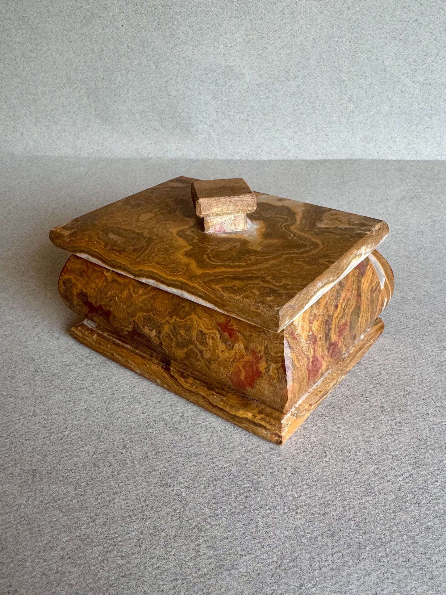 Three-quarter view of rust and clay-toned onyx box showing marbled veining