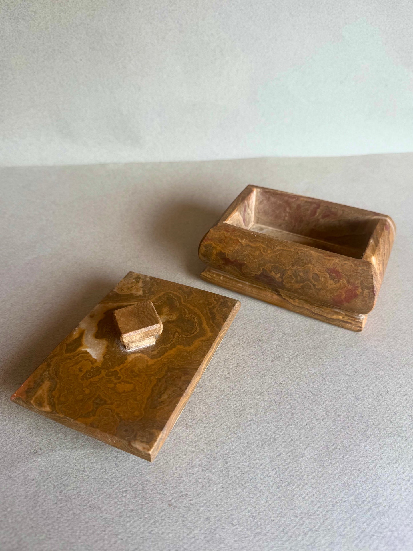 Open amber onyx box with lid placed beside, showing soft veining inside
