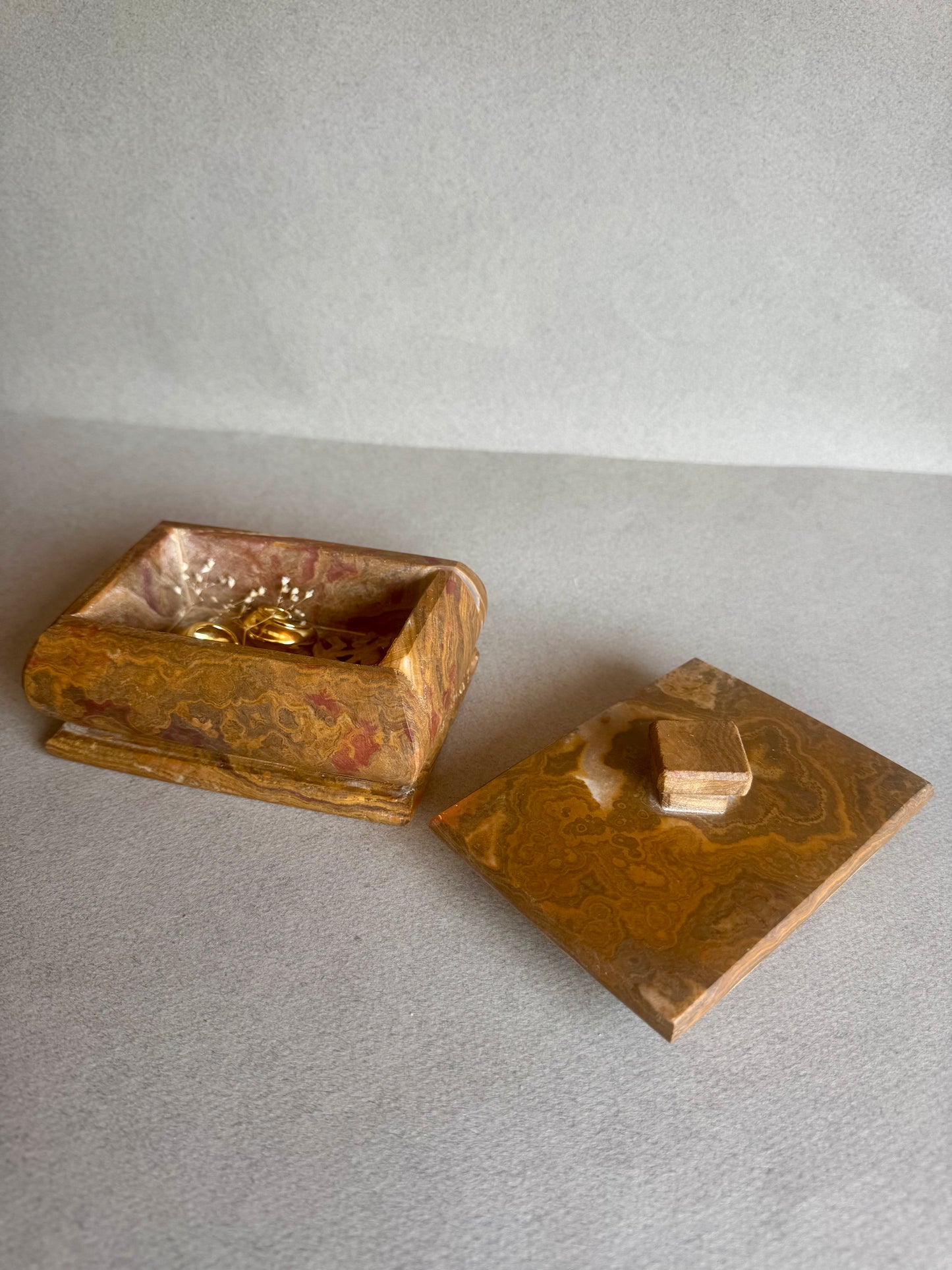 Open amber onyx box with lid placed beside, showing soft veining inside