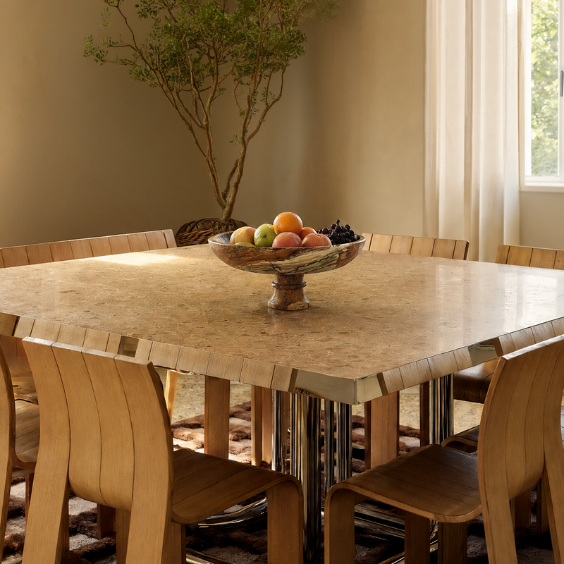 Dining room with a marble table and wooden chairs, featuring an onyx marble bowl of fruit.