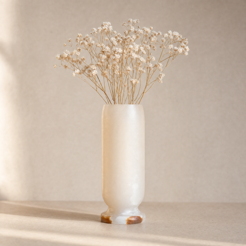 White onyx vase with dried flowers on a neutral background
