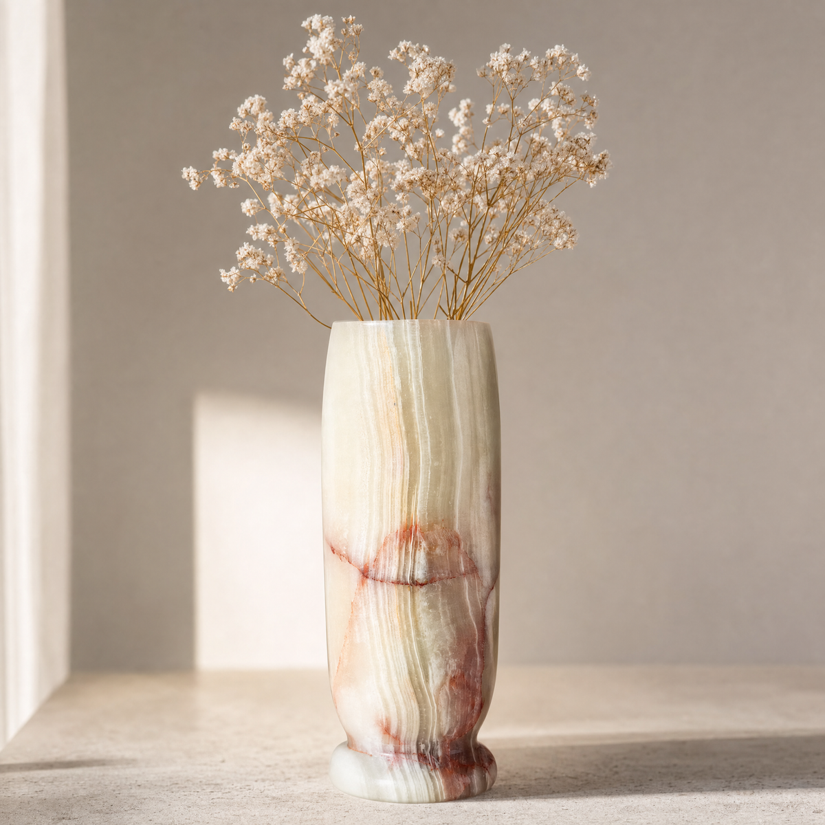 Decorative vase with marbled pattern containing dried flowers on a neutral background