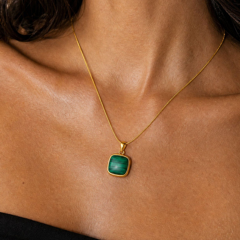 Gold necklace with a green malachite pendant on a person's neck