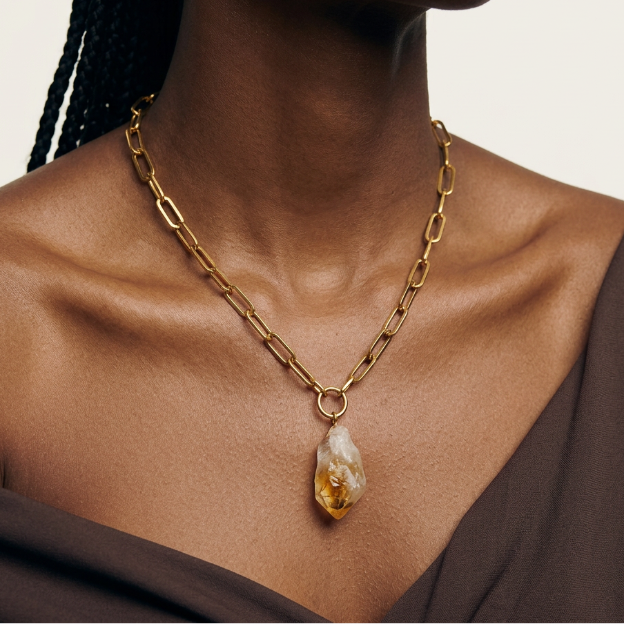 Gold chain necklace with a citrine pendant worn by a person
