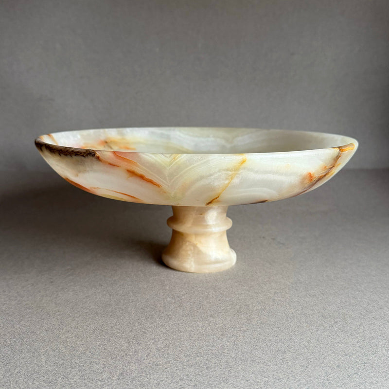Decorative onyx stone bowl with a pedestal base on a gray background