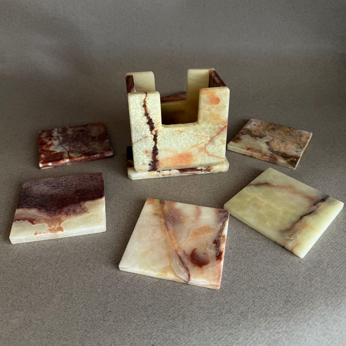 Cream, sage and plum onyx coaster set with all six coasters fanned around the holder.