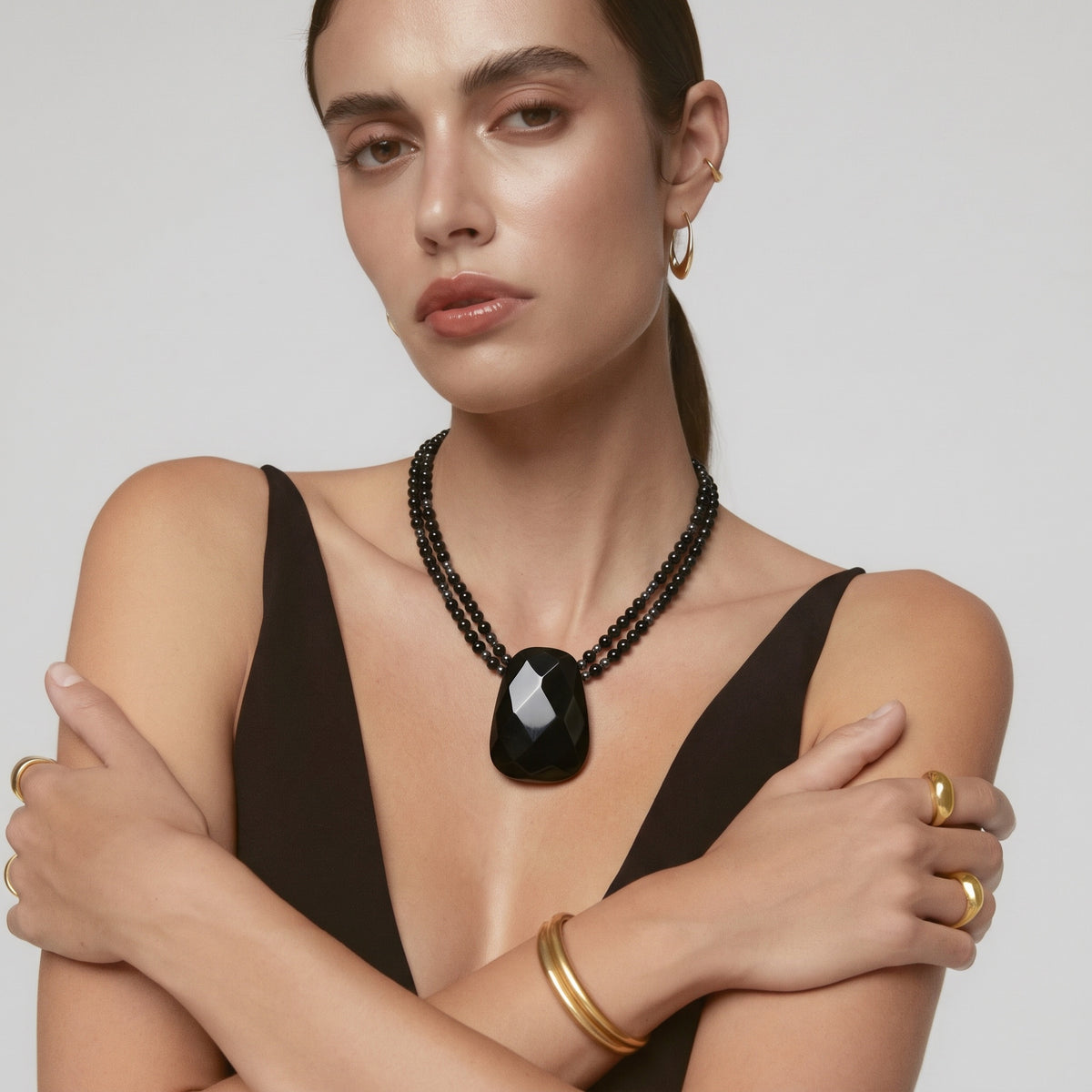Model wearing the faceted black onyx pendant necklace on a double strand of black beads
