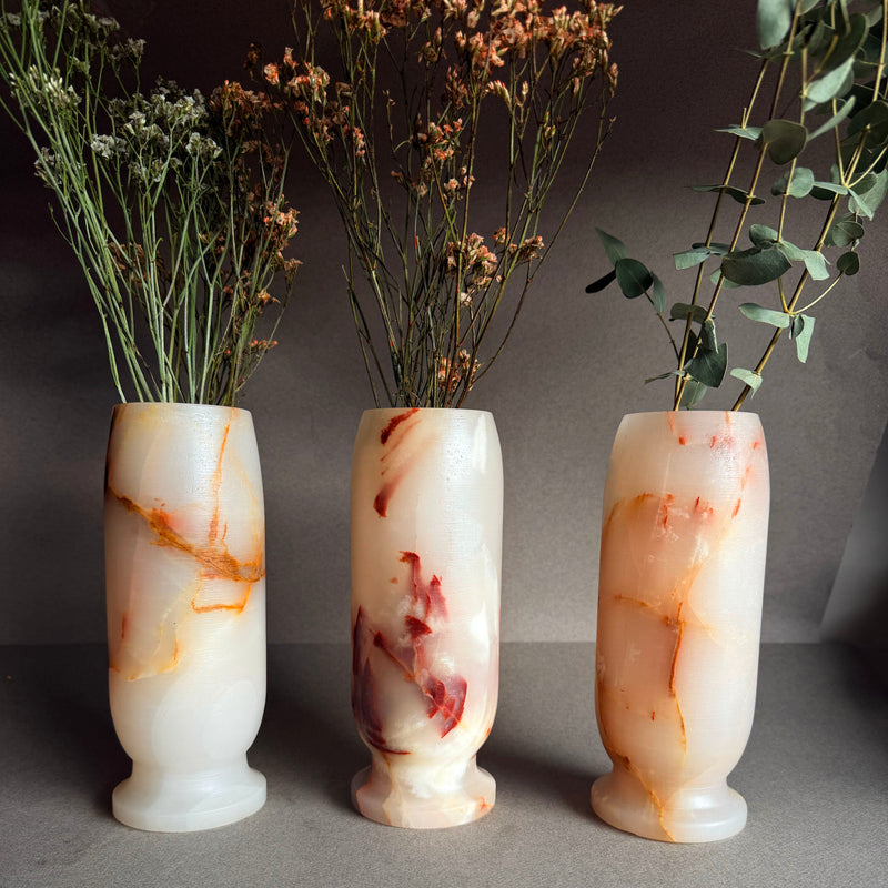 Three marble-textured vases with floral arrangements on a gray background