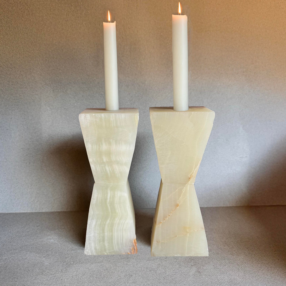 Pair of cream and nude green onyx taper candle holders on neutral backdrop