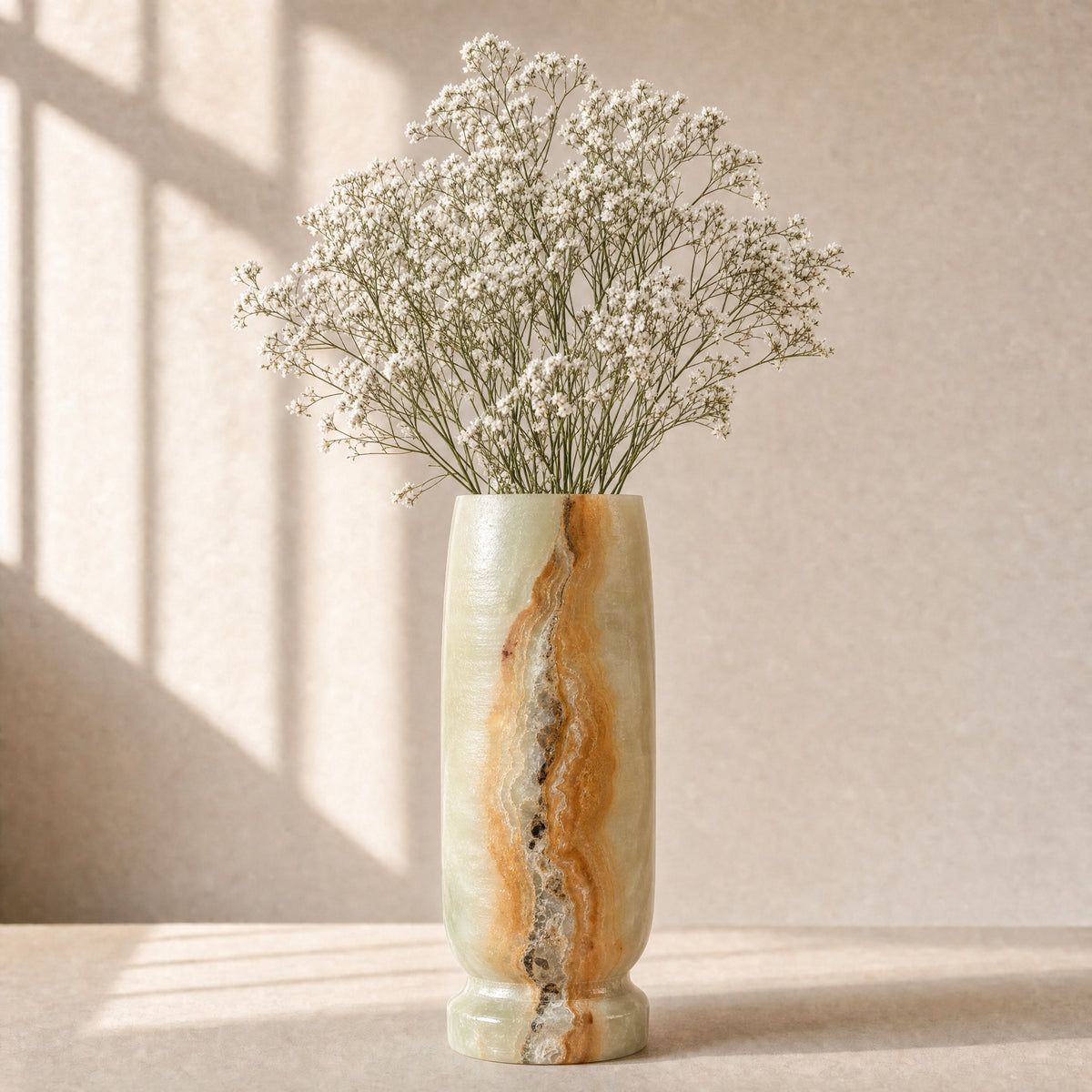 Decorative vase with wavy pattern containing small white flowers on a neutral background