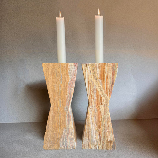 Pair of terracotta and sand-toned onyx taper candle holders styled on books with white taper candles – Side 4