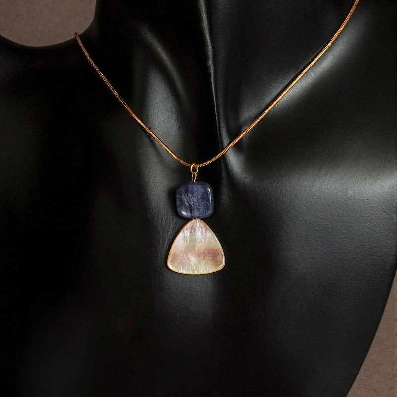 Mother of pearl and blue kyanite pendant necklace on gold filled snake chain displayed on neutral stone surface