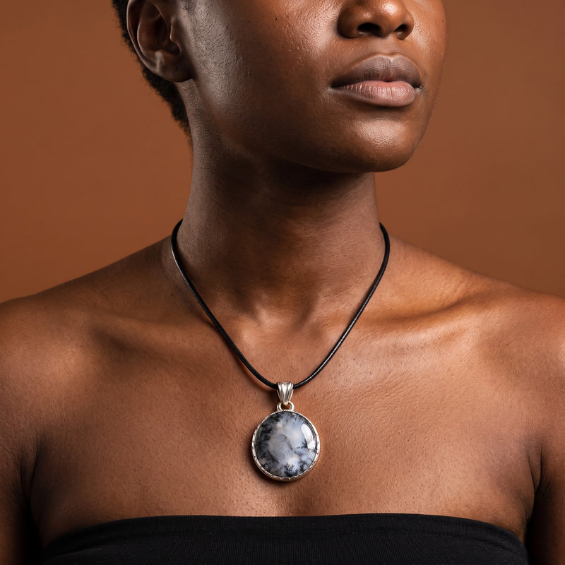 Blue, white and ink dendritic opal round pendant in a sterling silver bezel on a short black cord, worn at the collarbone