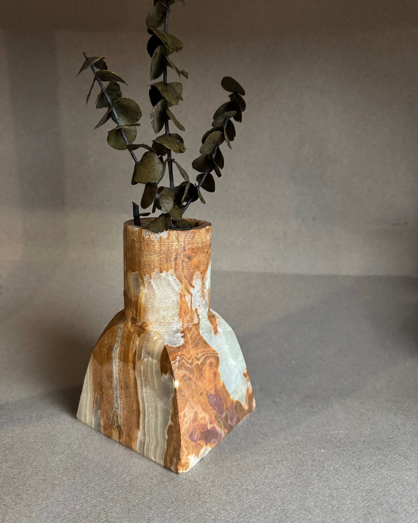 Vase made of natural onyx stone with a plant on a gray background