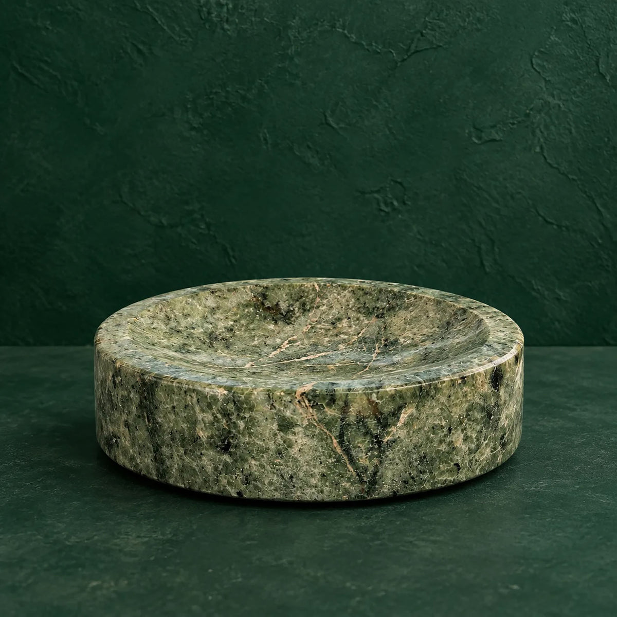 Fern green marble catchall bowl with cream and gold veining, front view against an emerald ground