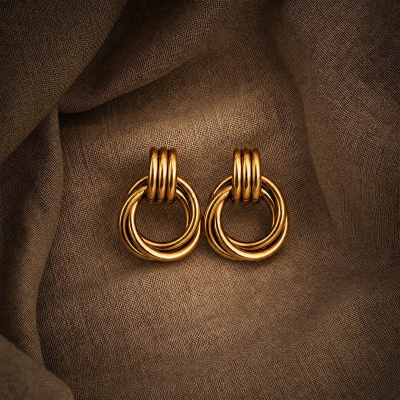 Pair of chunky vintage gold knot earrings on a brown fabric background