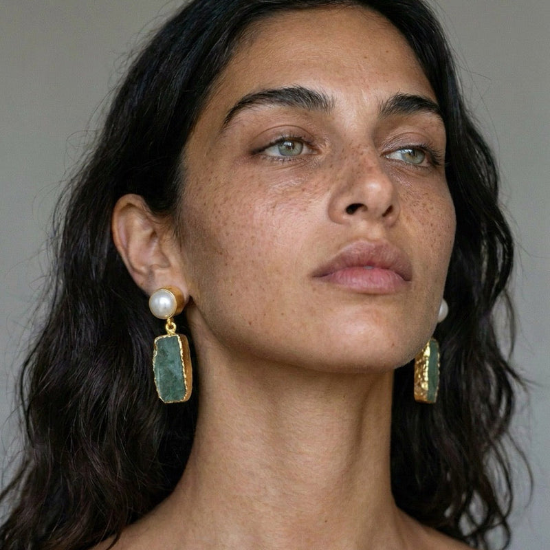 Model wearing a green aventurine and freshwater pearl drop earring in 22k gold plate, against a gray background