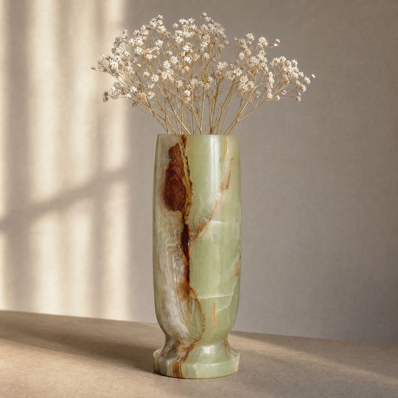 Decorative vase with a natural stone pattern containing dried flowers on a neutral background