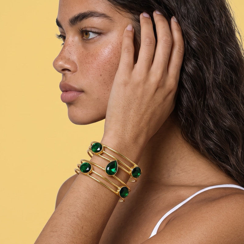 Model shown in profile with hand in hair, wearing the emerald quartz cuff bracelet.