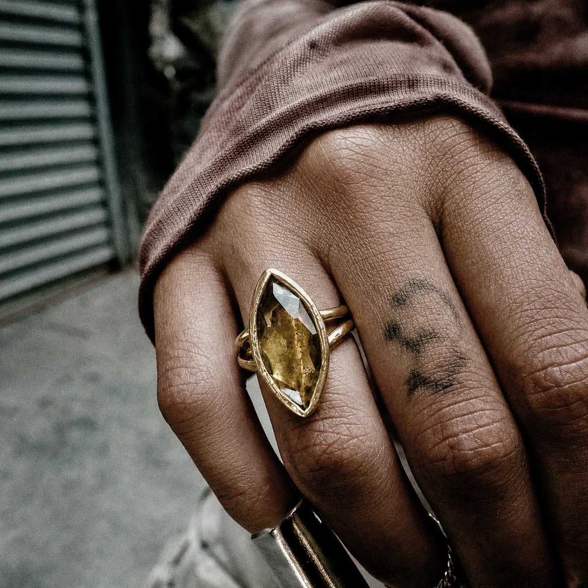 Honey quartz marquise ring in gold vermeil worn on a hand, the rose-cut stone set in a hand-etched bezel, against a dusty pink sleeve.