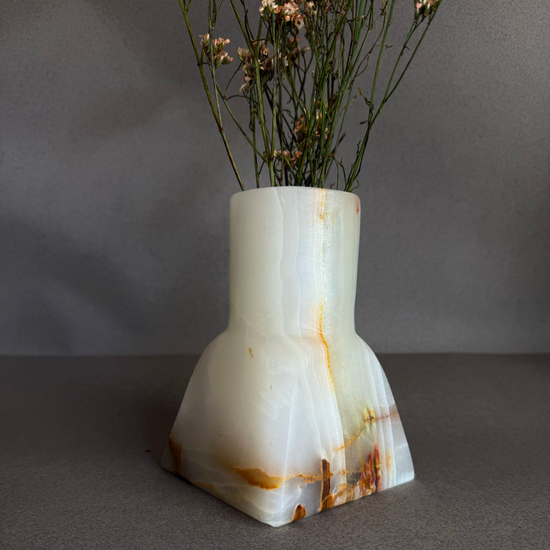 Marble-patterned white onyx vase with dried flowers on a gray background