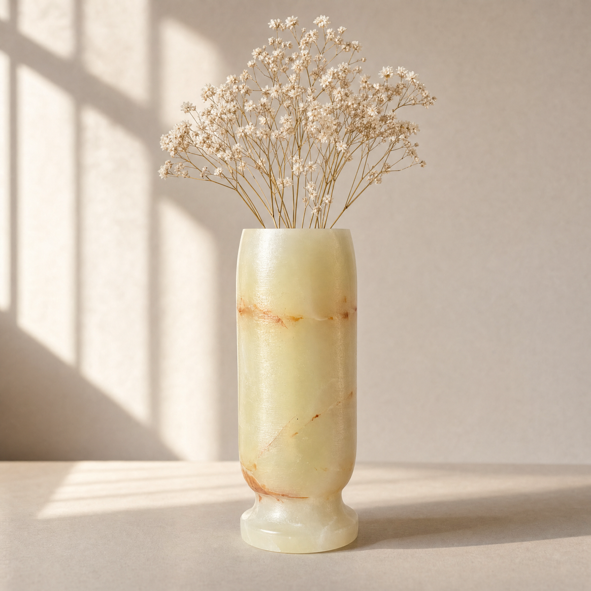 Marble-patterned light green onyx vase with dried flowers on a neutral background