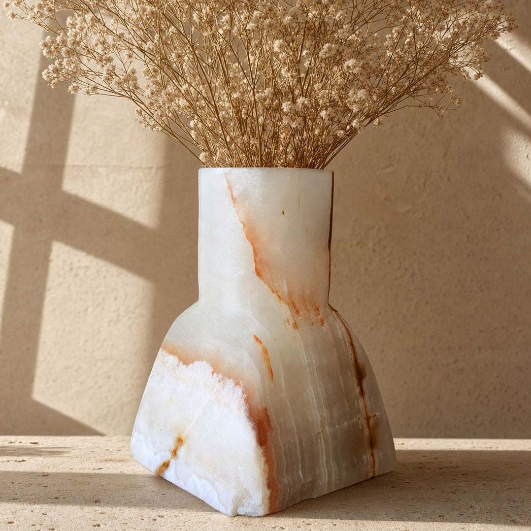 Milk-white onyx Dune Vase with a fine amber vein running down one side, shown on a sunlit stone surface.