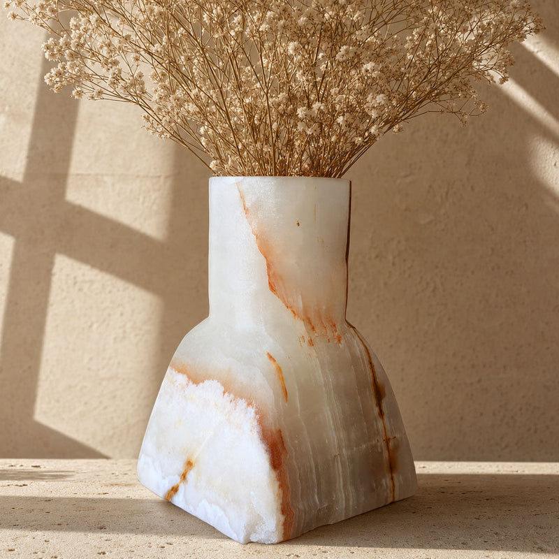 Milk-white onyx Dune Vase with a fine amber vein running down one side, shown on a sunlit stone surface.